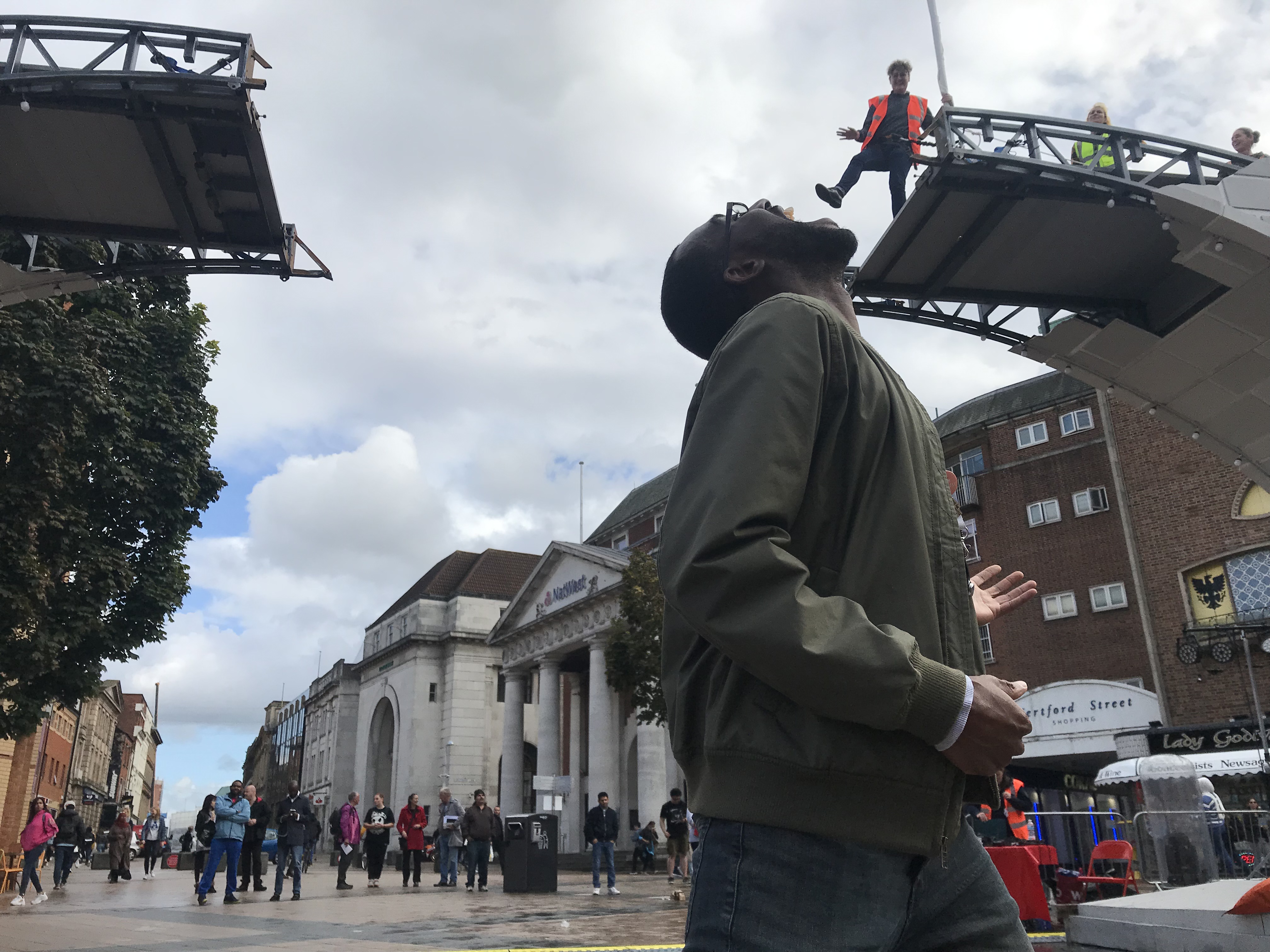 A man stands under the bridge with his mouth wide open. Above, someone on the bridge appears to be putting his foot into the man's mouth. It is a fun trick on perspective!