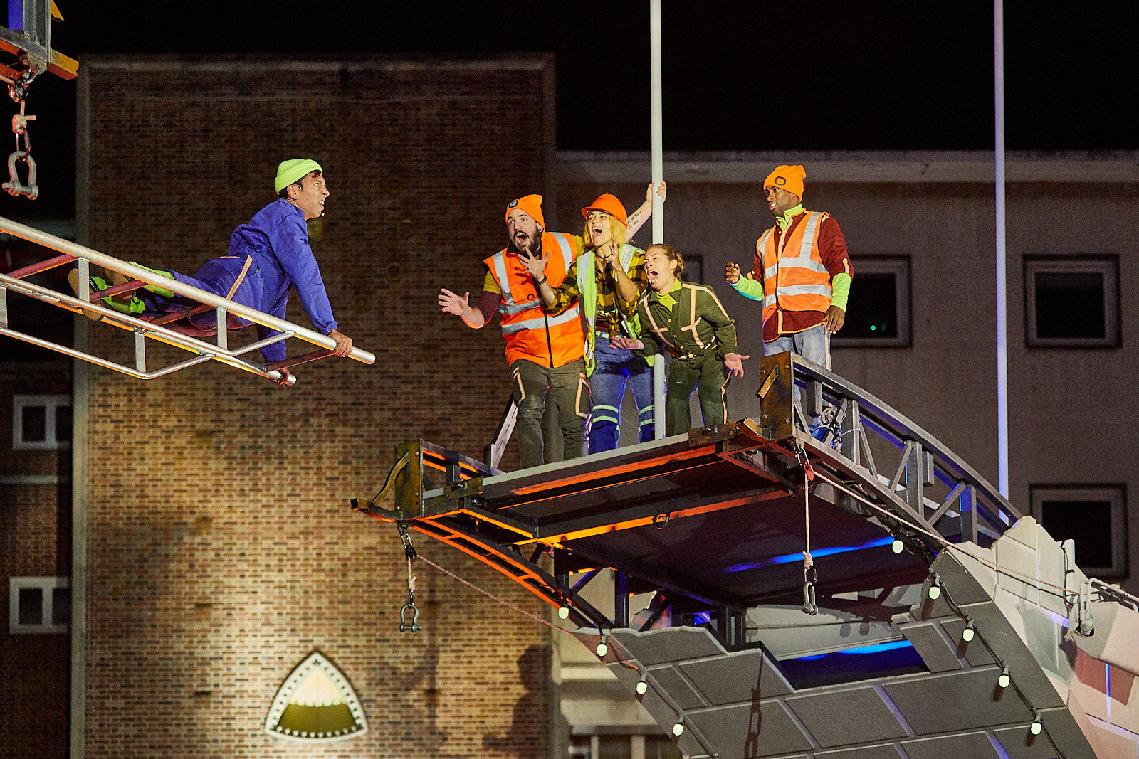 An acrobat lies on a ladder suspended on the broken bridge several feet above the ground