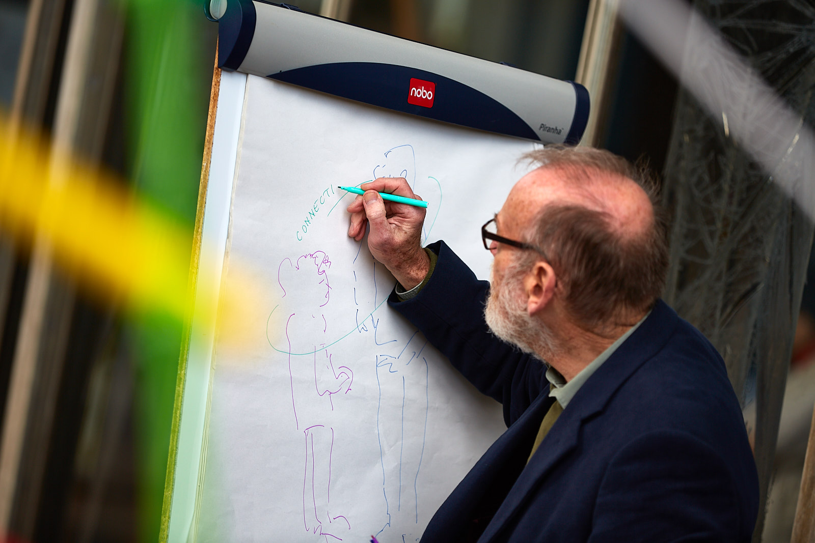 Visual artist Tom Jones makes a line drawing on a flip chart. He is capturing stories of bridge-building. The photo was taken at the Festival of Imagineers in 2018.