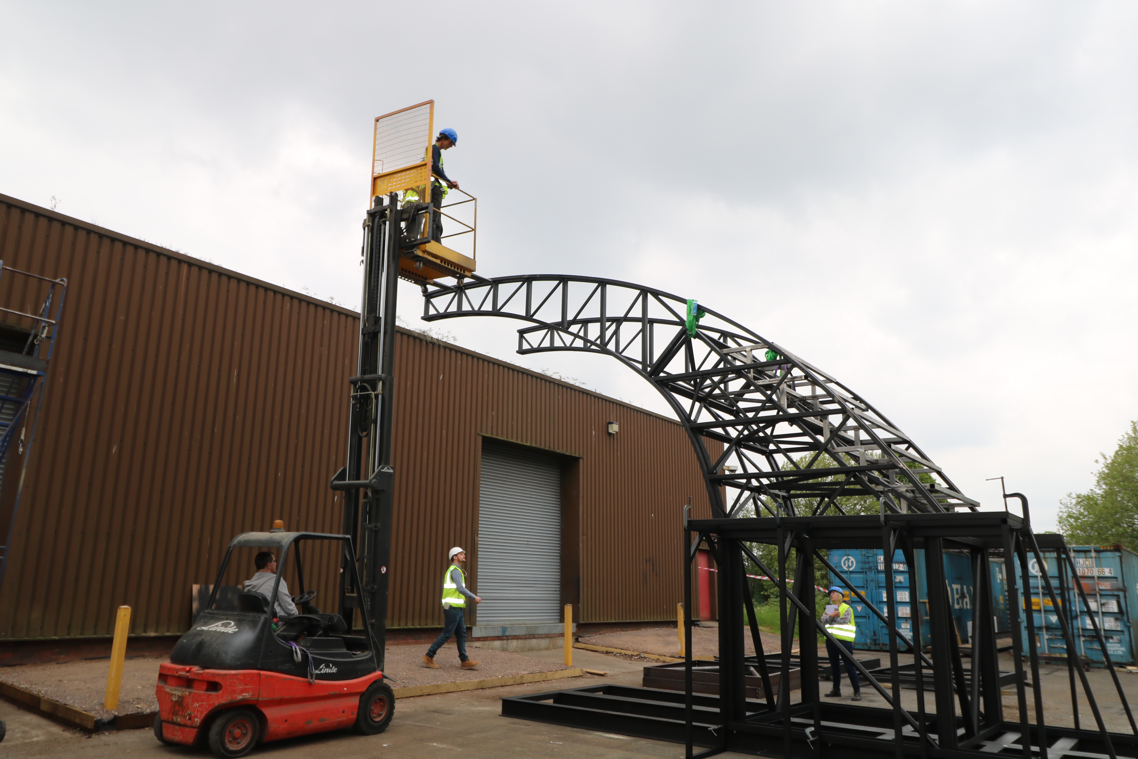 A member of Imagineer's production team is high up on a access platform, inspecting the partially-built Bridge from above. We see the framework of one half of the Bridge. 