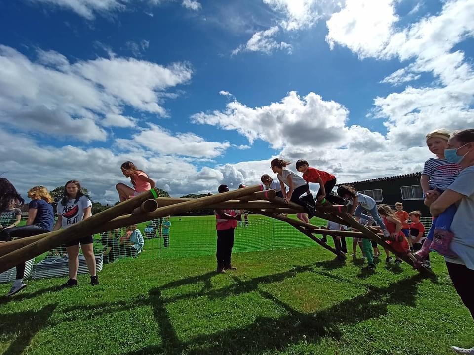 School children climb over a self-supporting bridge, guided by their teacher.